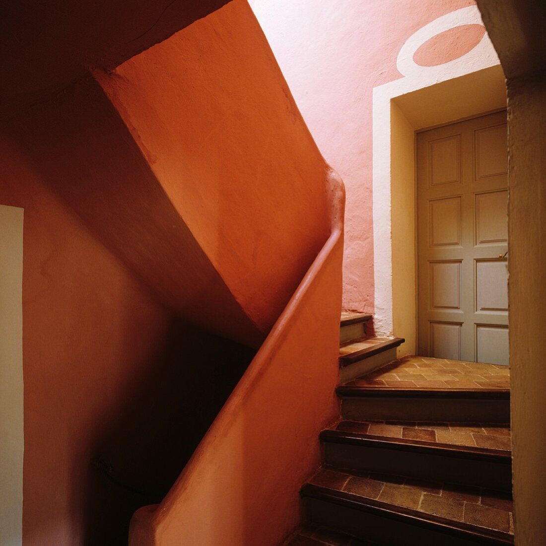 Panelled front door in stairwell with limestone walls and tiled stair treads