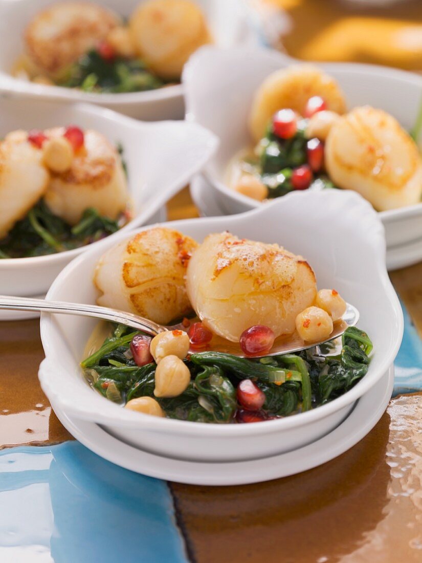 Fried scallops on a bed of spinach with chickpeas and pomegranate seeds
