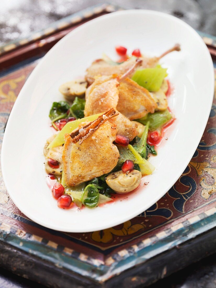 Quail on a leek and mushroom medley with pomegranate seeds