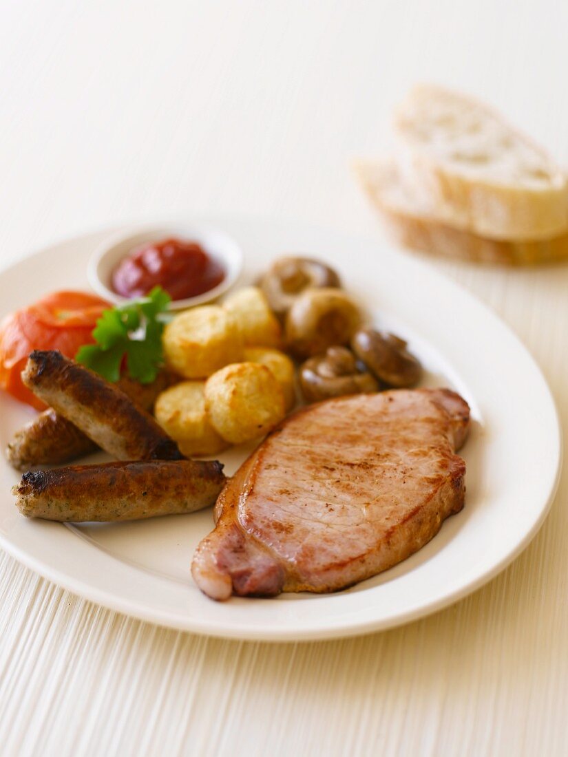 Englisches Frühstück mit Schinken, Würstchen, Bratkartoffeln und Pilzen