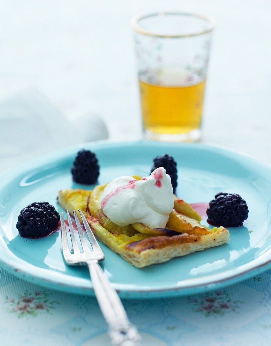 A slice of apple cake with cream and blackberries