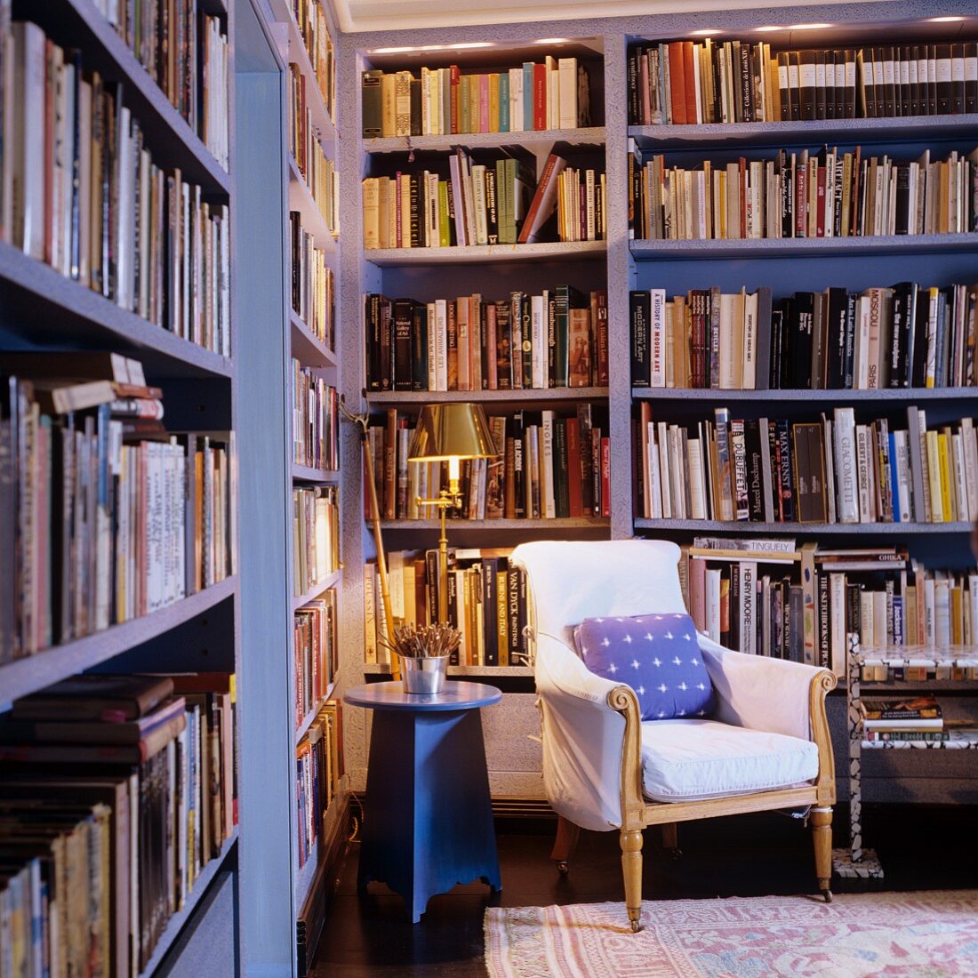 Upholstered antique armchair and side table in corner of library