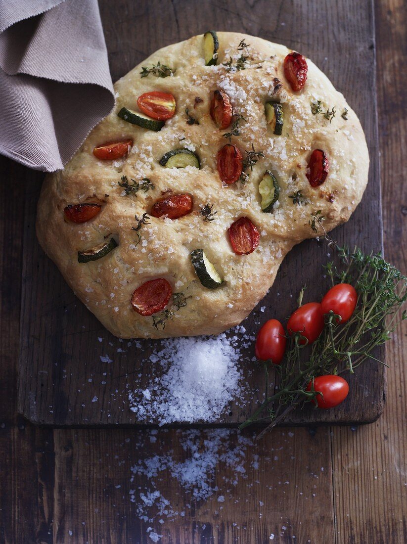Focaccia with salt, plum tomatoes, courgettes and herb