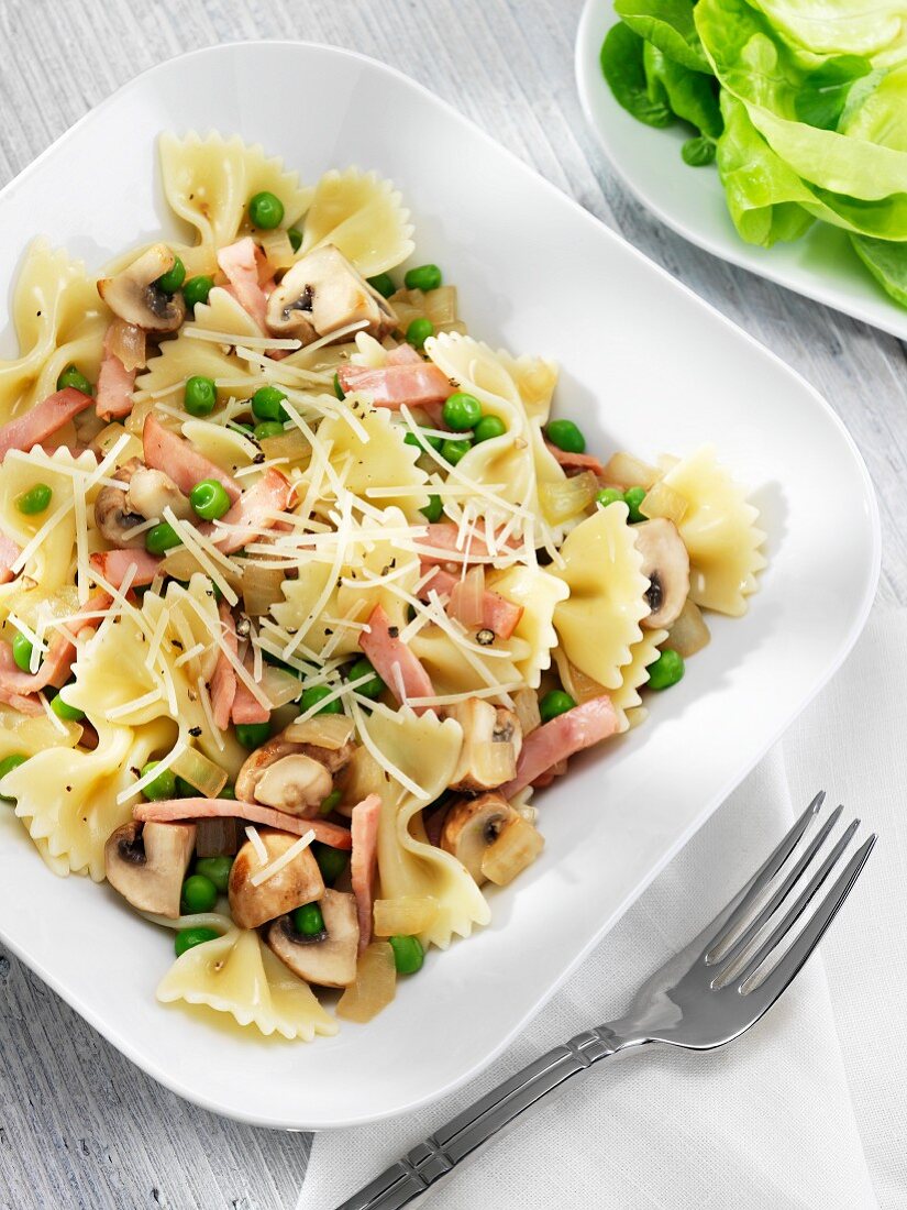 Bow Tie Pasta with Peas, Ham and Mushrooms in a White Dish; Fork