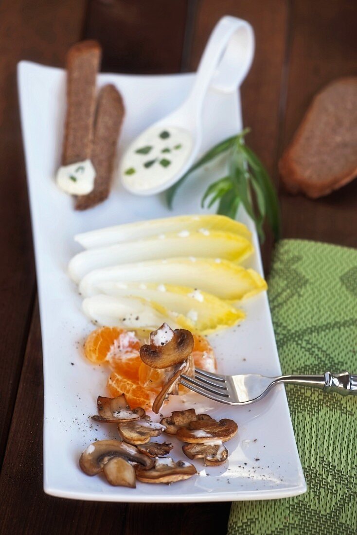 Salatplatte mit Chicorée, Mandarinen, Pilzen & Brotstreifen