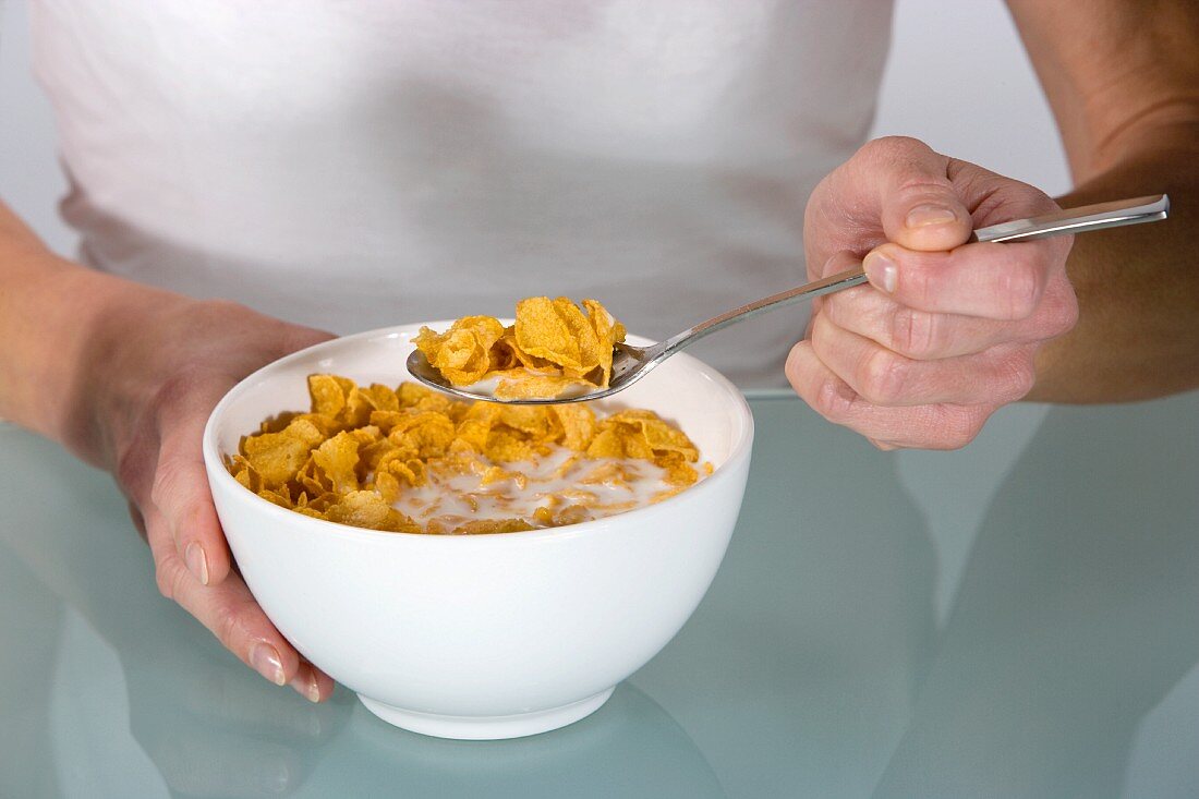 A woman eating cornflakes with milk