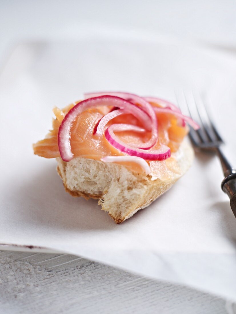 A piece of white bread topped with smoked salmon and onions