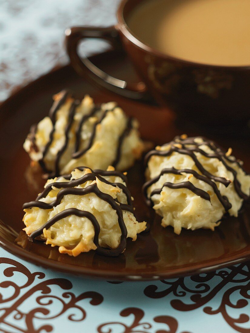 Coconut macaroons decorated with chocolate stripes and a cup of coffee