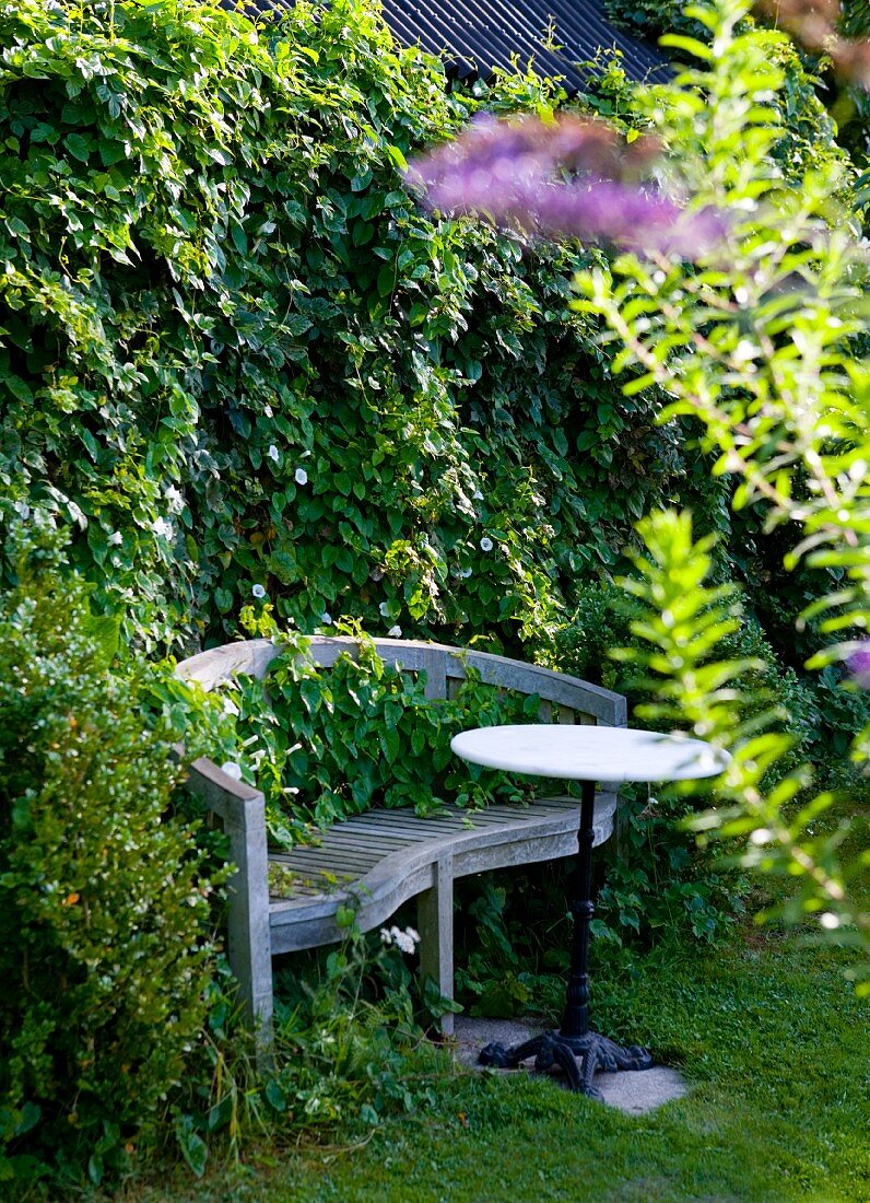 Alte Gartenbank und Bistrotisch vor Hecke