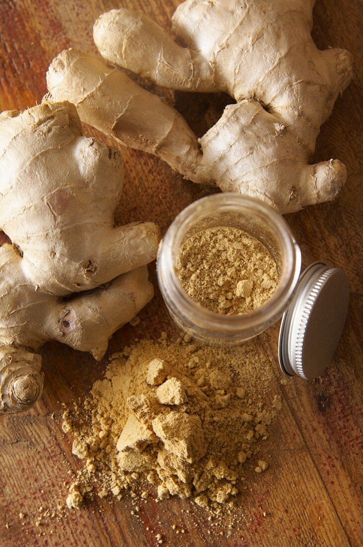 Ginger roots and ground ginger on a wooden surface