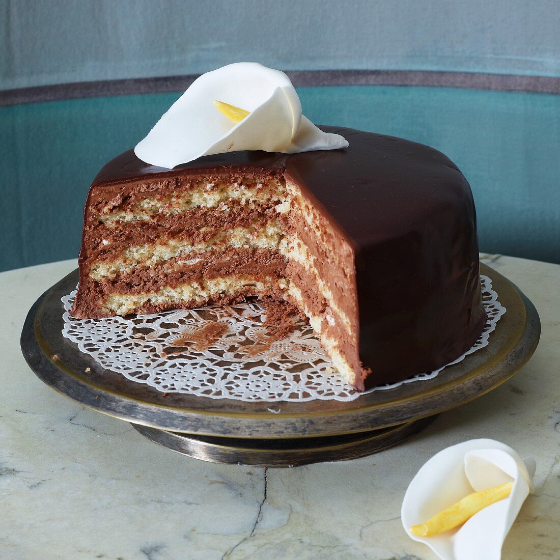 An almond and chocolate cake decorated with a calla lily, sliced