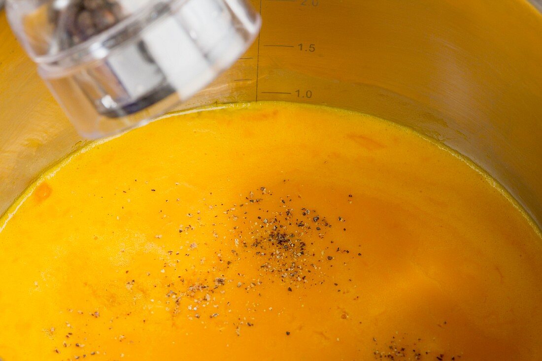 Cream of pumpkin soup being seasoned