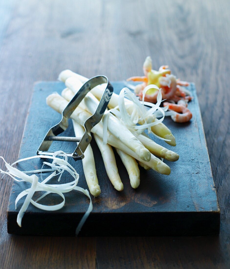 White asparagus and a peeler on a wooden board