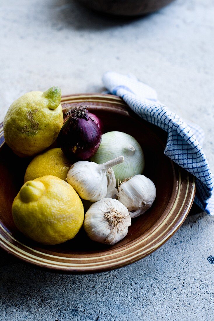 Zitronen, Knoblauch & Zwiebeln in einer Tonschale