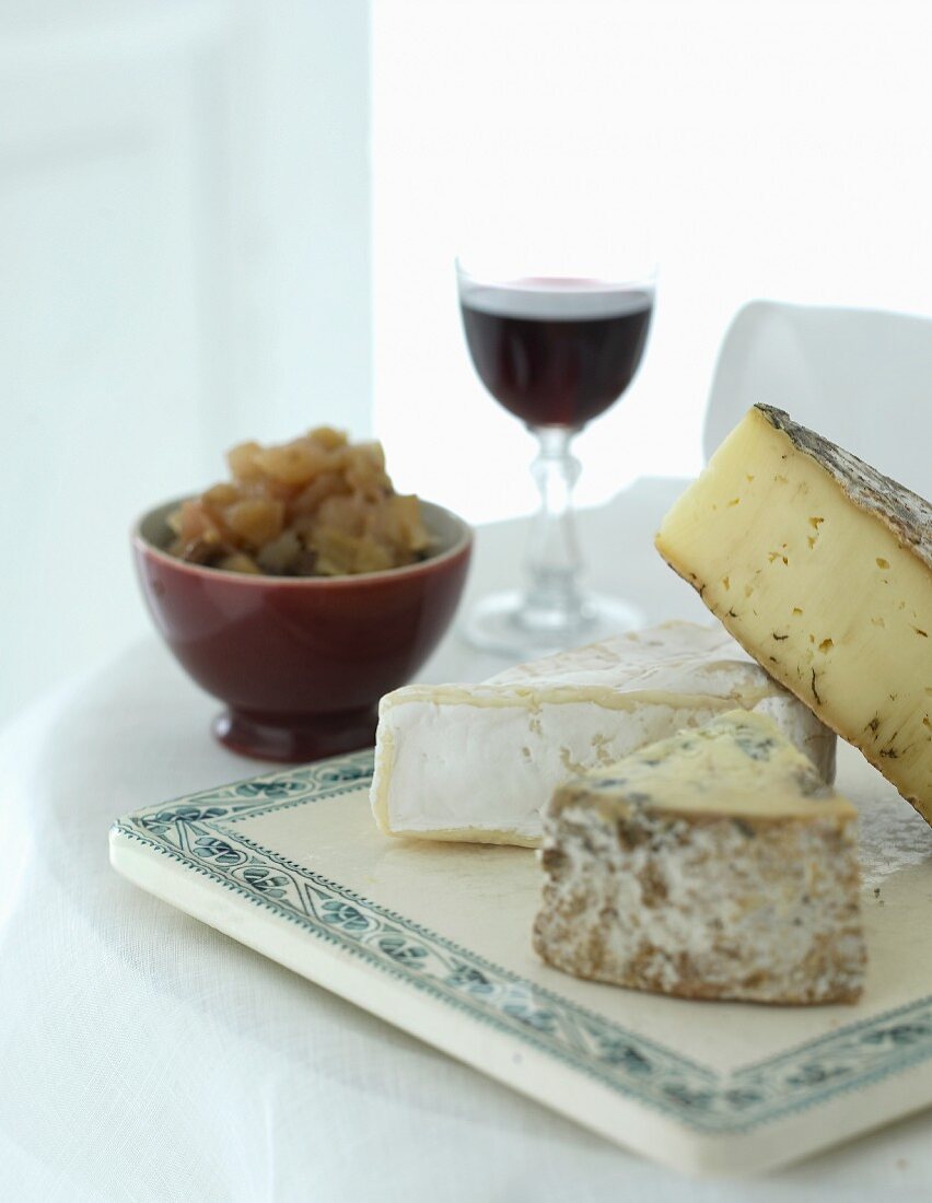 A cheese platter with chutney and red wine