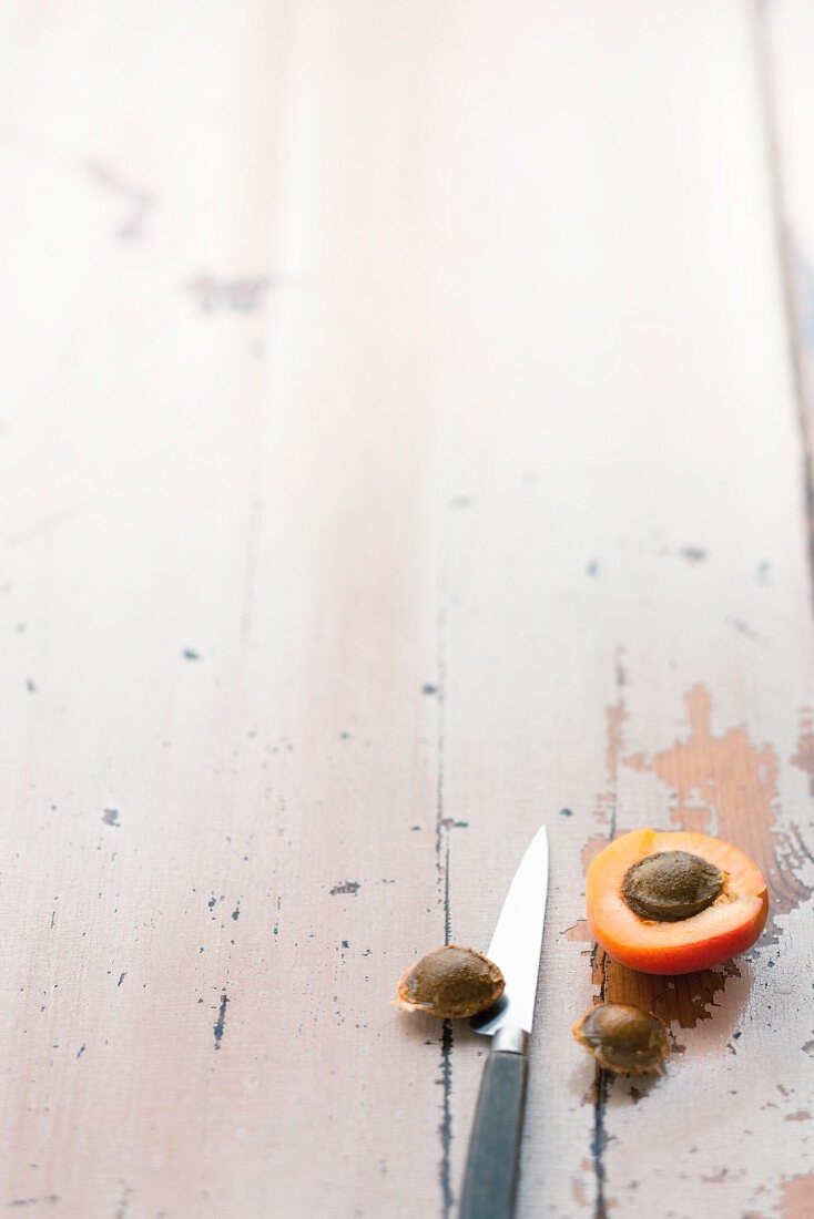 Half an apricot and an apricot stone on a wooden surface