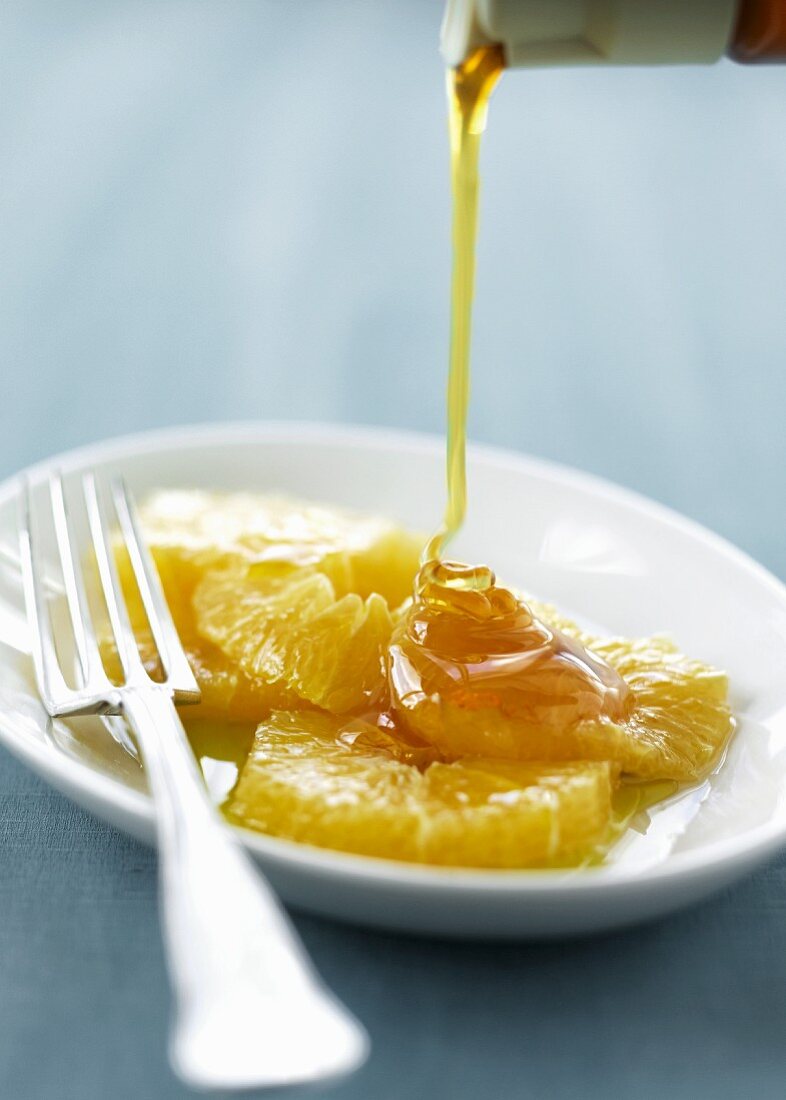 Honig fließt auf Orangenscheiben