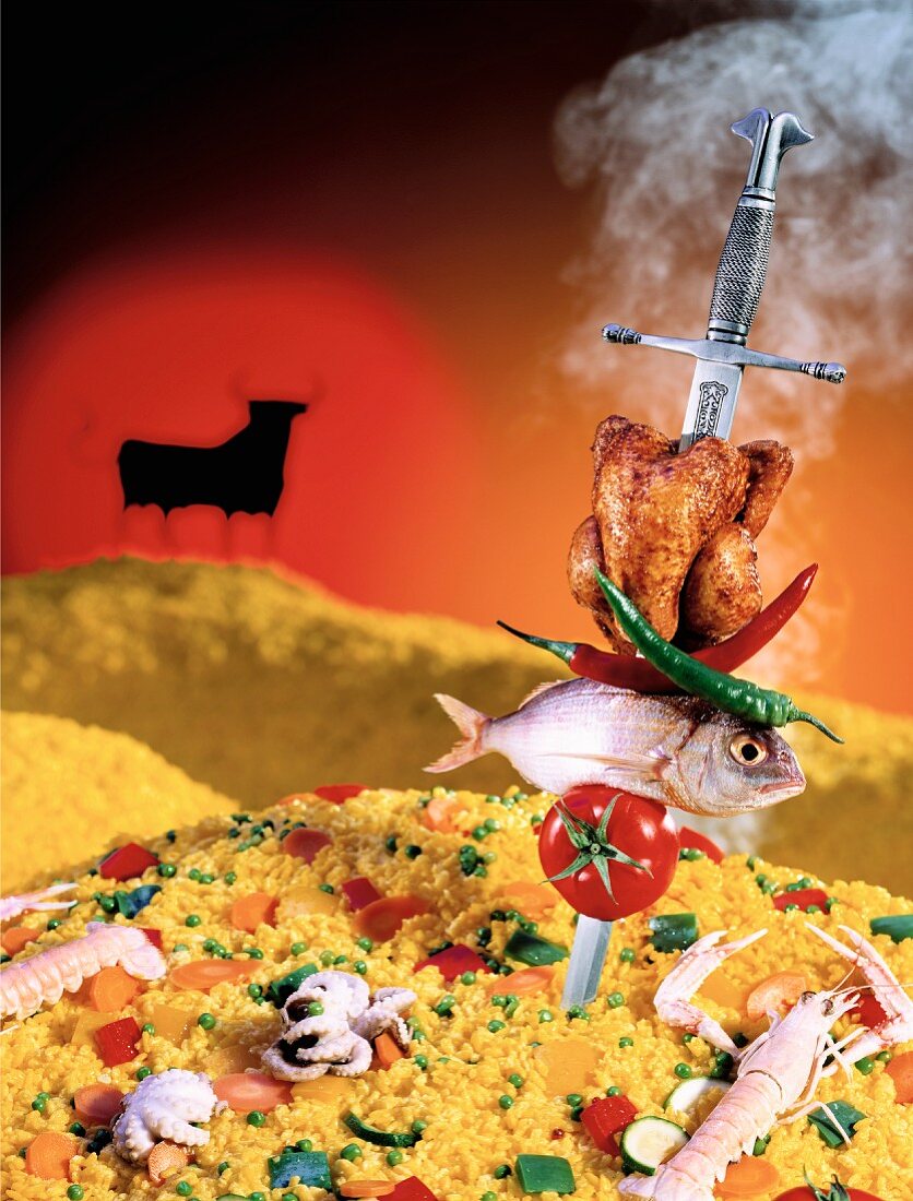 A fish and a chicken skewered onto a sword and stuck in a mountain of paella (Spain)
