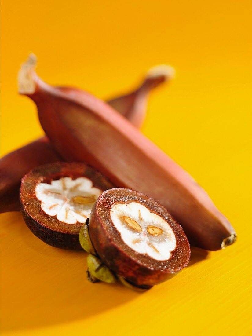 Halbierte Mangostane und rote Bananen