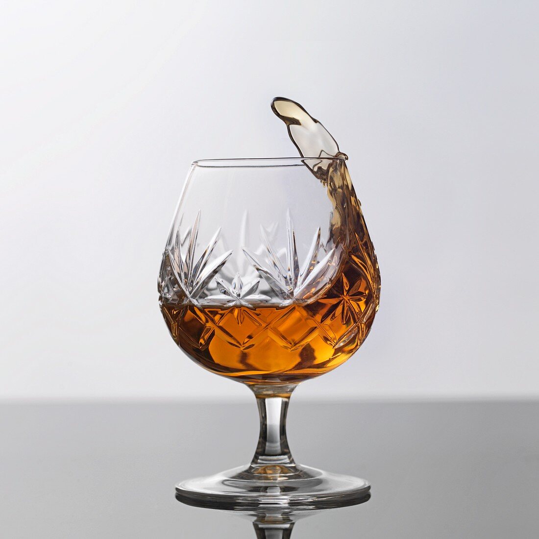 A glass of brandy splashing out of a glass