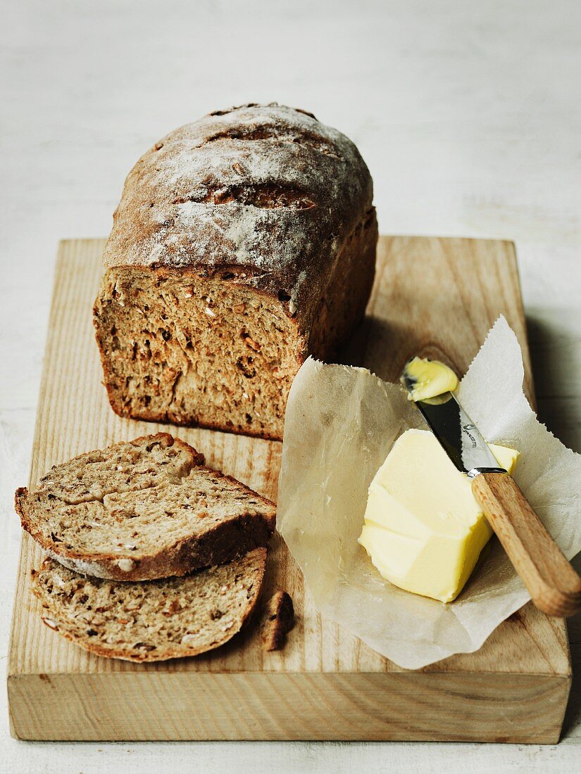 Vollkornbrot und Butter auf altem Schneidebrett