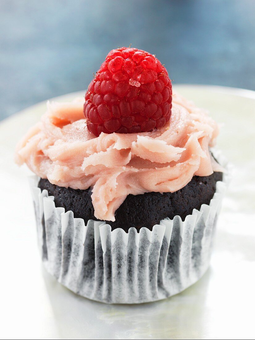 A chocolate cupcake with raspberry cream and a raspberry