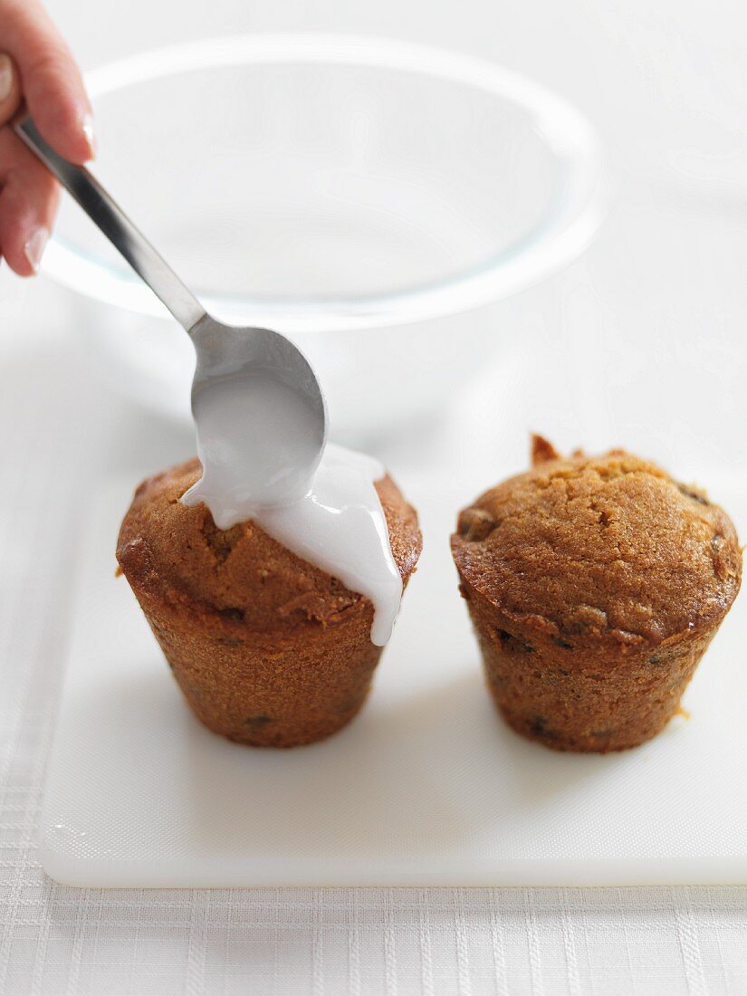 Mini Christmas cakes being decorated with icing sugar