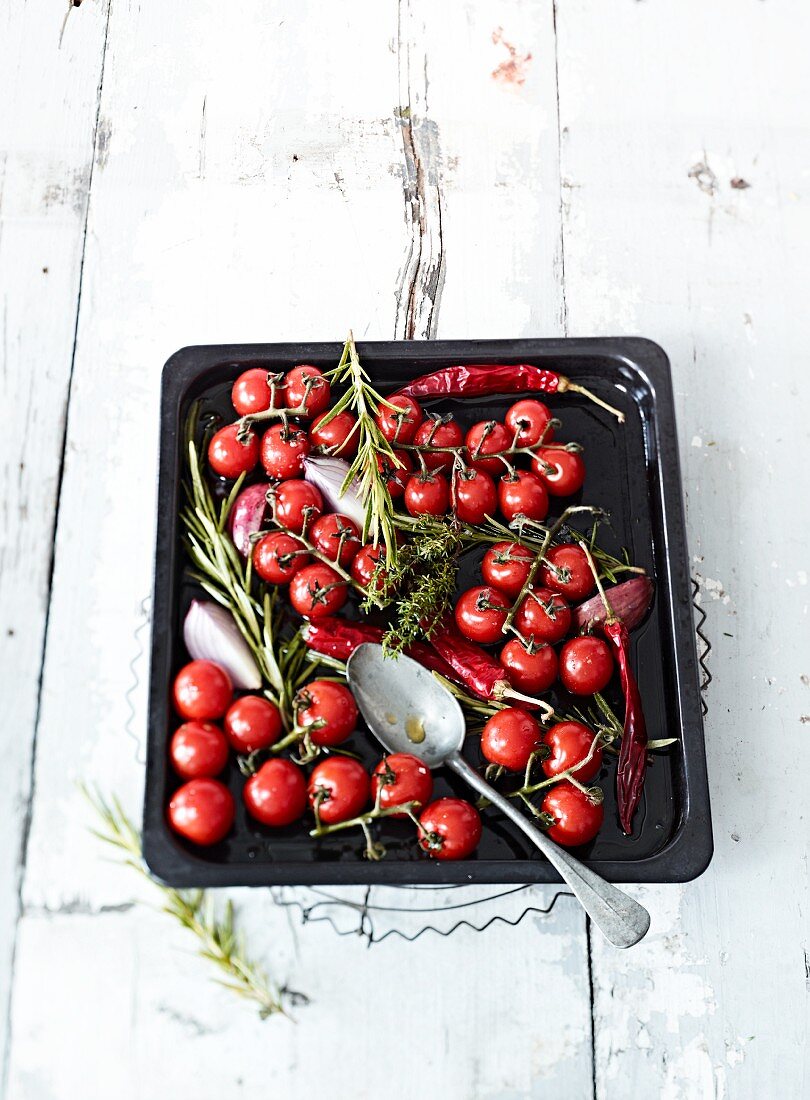 Cherry tomatoes with herbs and chilli pepper on a baking tray