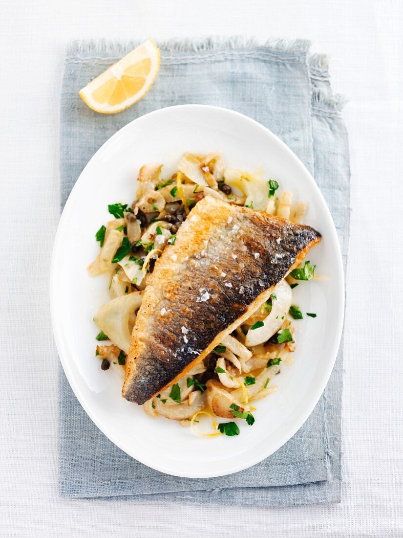 Fried sea bass fillet on a bed of vegetables