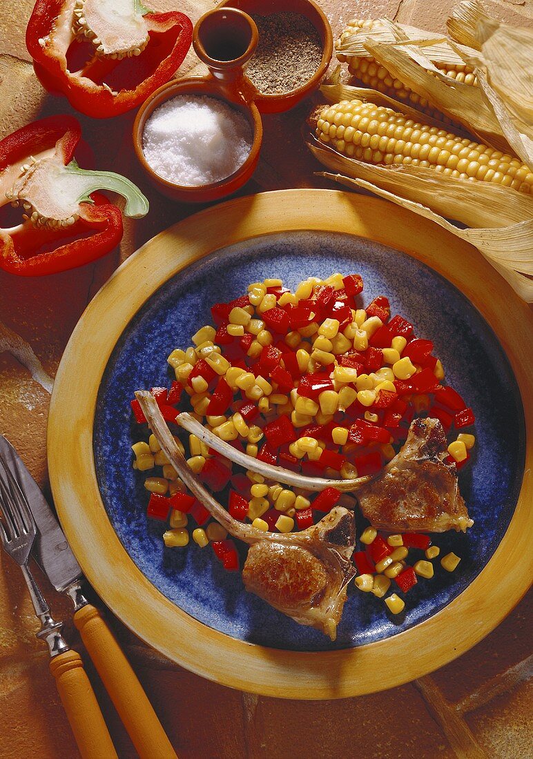 Ein Teller mit Lammkoteletts auf Paprika-Mais-Gemüse