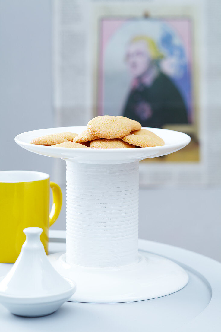 A homemade cake stand made from two plates and a white-painted tin can