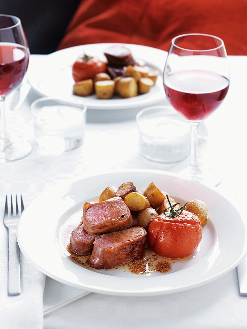 Fillet of lamb wrapped in ham with tomatoes and potatoes