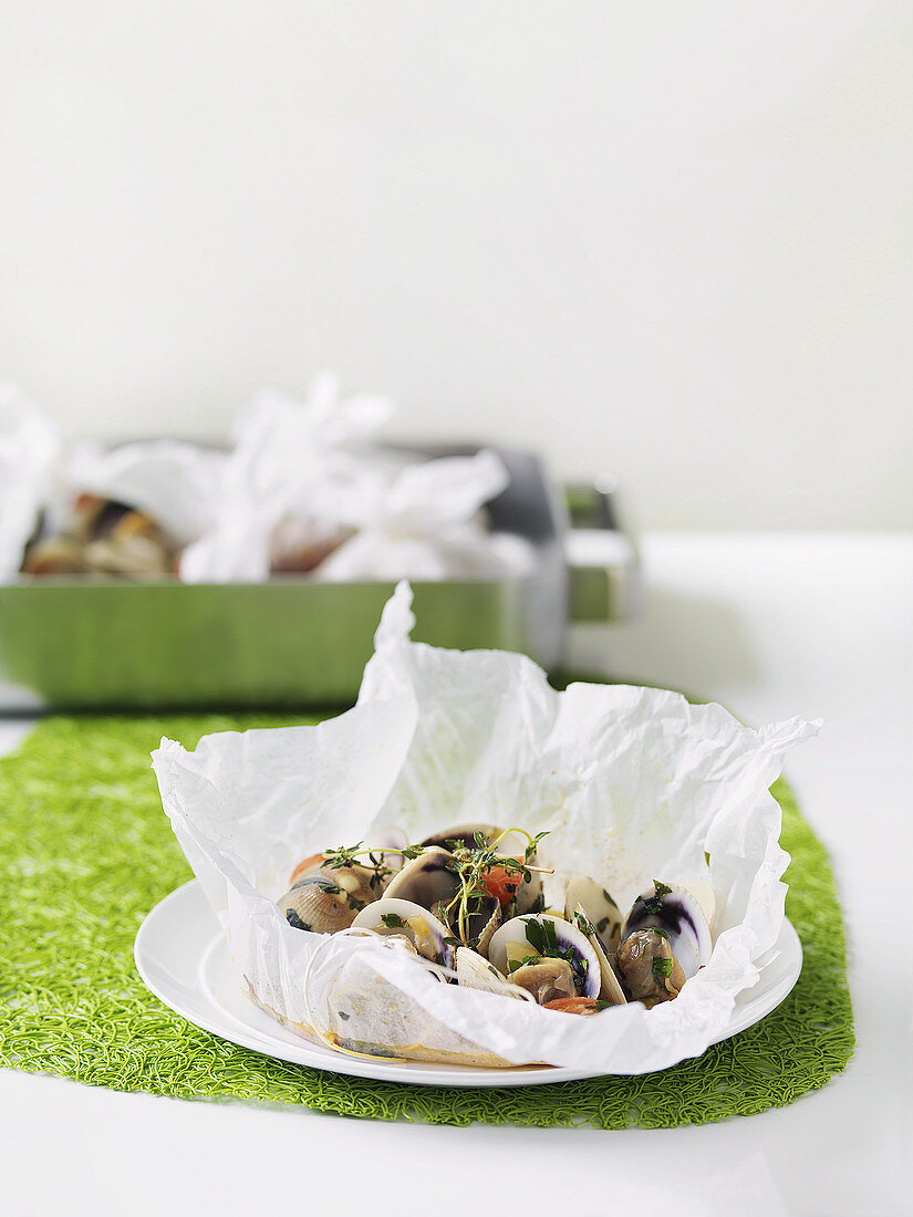 Venus clams with celery and cherry tomatoes in baking paper