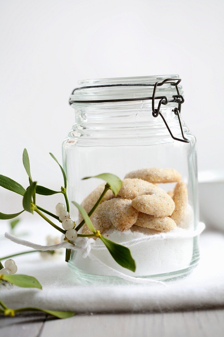 Sugar and vanilla biscuits in a flip top jar with a sprig mistletoe in front of it