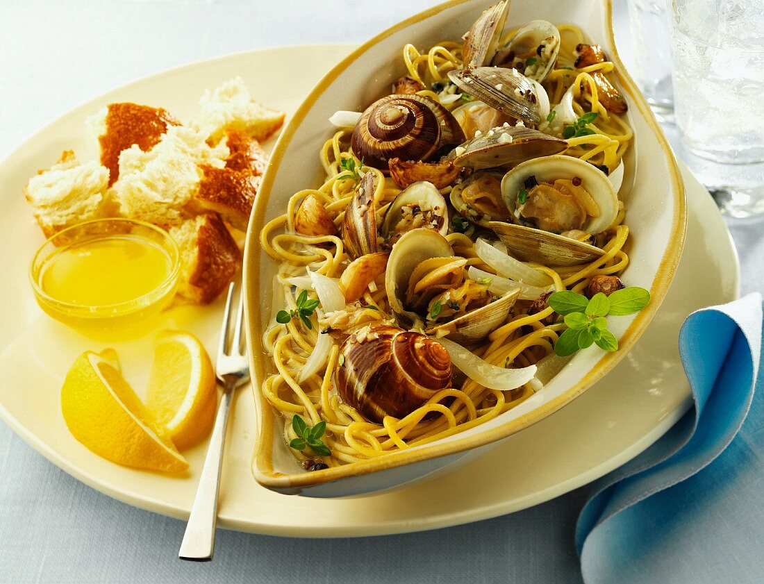 Clams and Escargot with Linguini in a Bowl; Bread and Lemon Slices