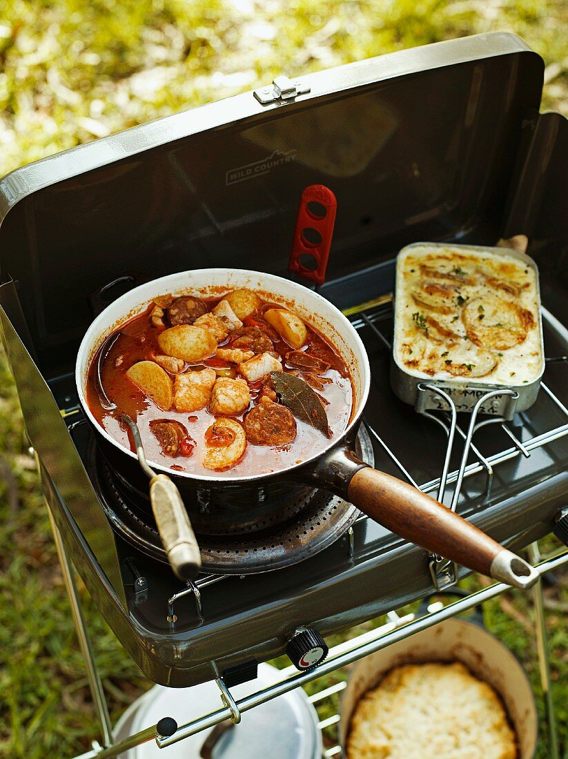 Fish stew with chorizo and gratinated potatoes on a camping cooker