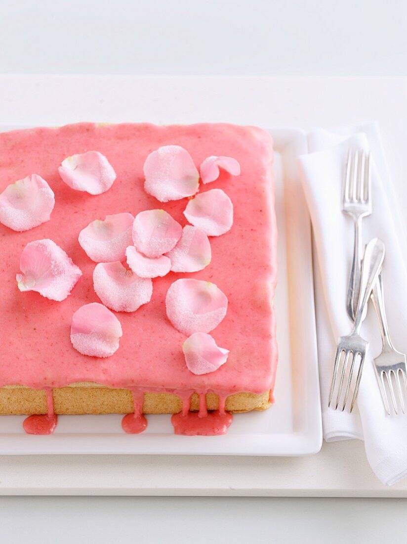 Biskuitkuchen mit Erdbeerglasur und Rosenblättern