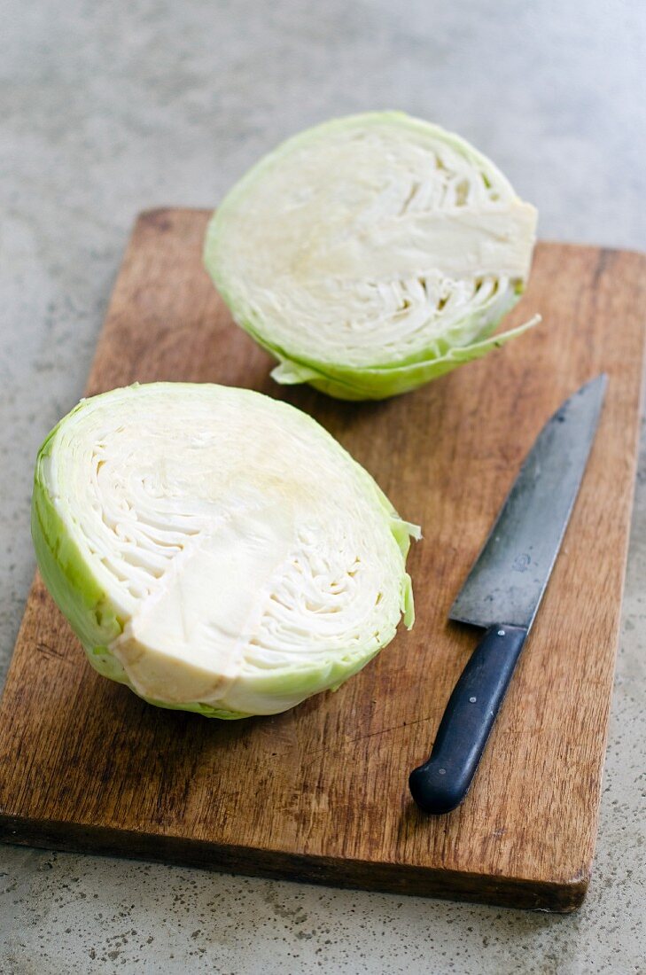 White cabbage, halved, on chopping board