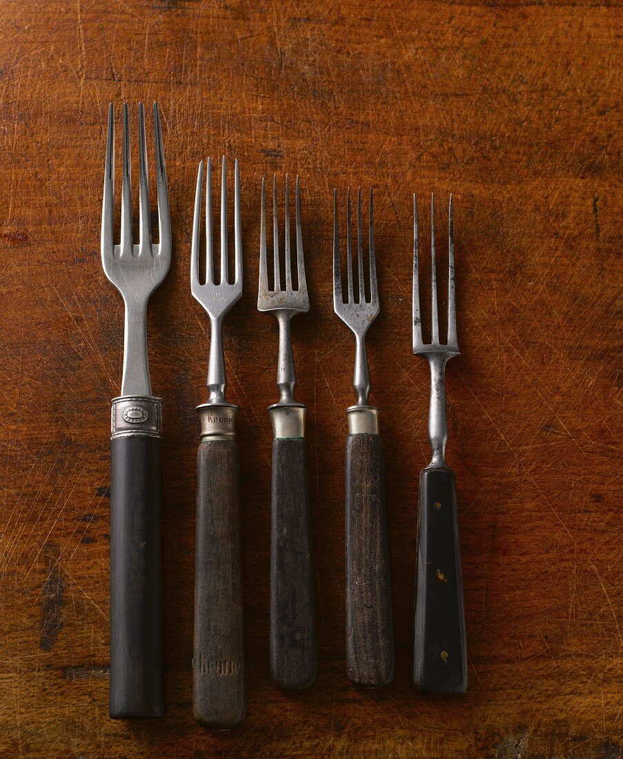 Five old forks on a wooden surface