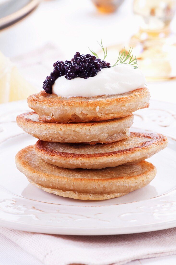 A stack of blinis topped with sour cream and caviar