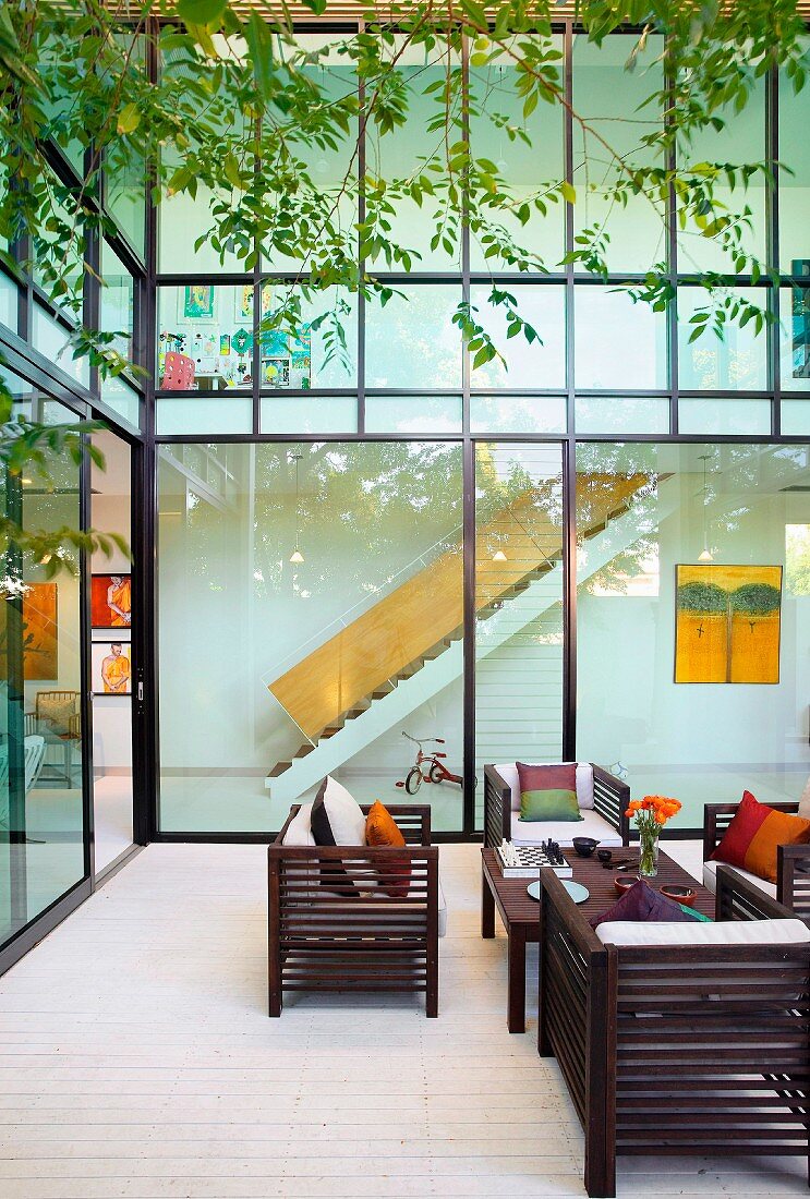 Möblierter Innenhof mit Blick durch Glasfassade auf Treppe im Innenraum