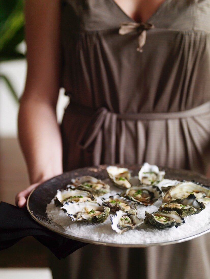 A woman serving oysters with balsamic vinegar