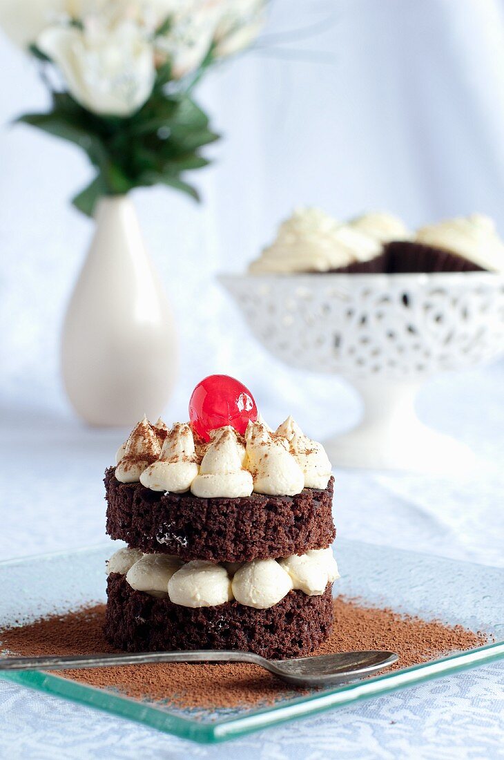 A chocolate cake with vanilla cream and a cocktail cherry