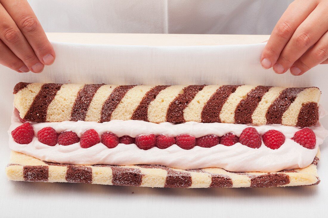 Schwarz-weiss gestreifte Biskuitroulade mit Himbeerfüllung zubereiten