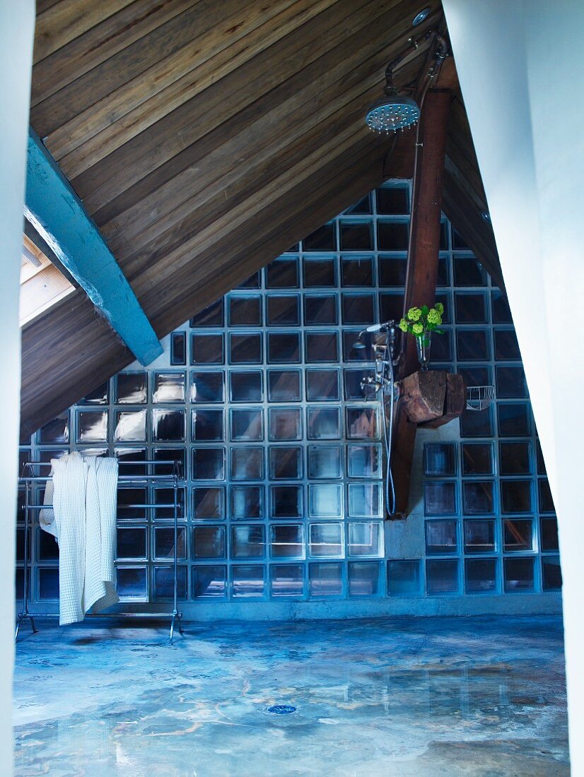 Attic space with glass brick partition and wood-panelled sloping ceiling