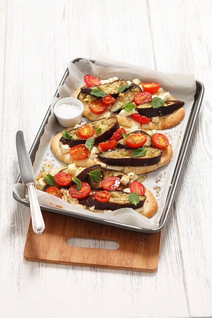 Pita bread pizza topped with aubergines, tomatoes and feta cheese