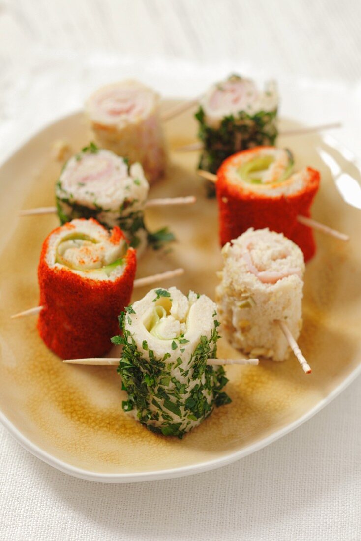 Toast rolls filled with ham and cheese, covered with pepper, parsley and almonds
