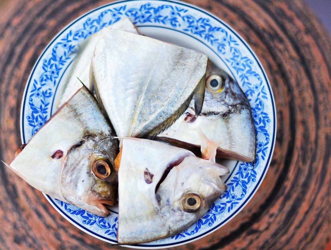 Raw fish heads (Thai butter fish) on a plate