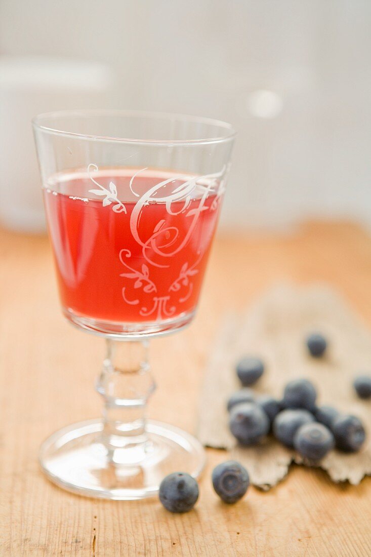A glass of blueberry juice and fresh blueberries