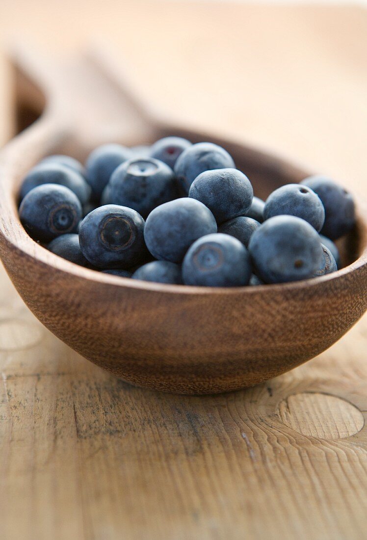 Fresh blueberries in a wooden ladle